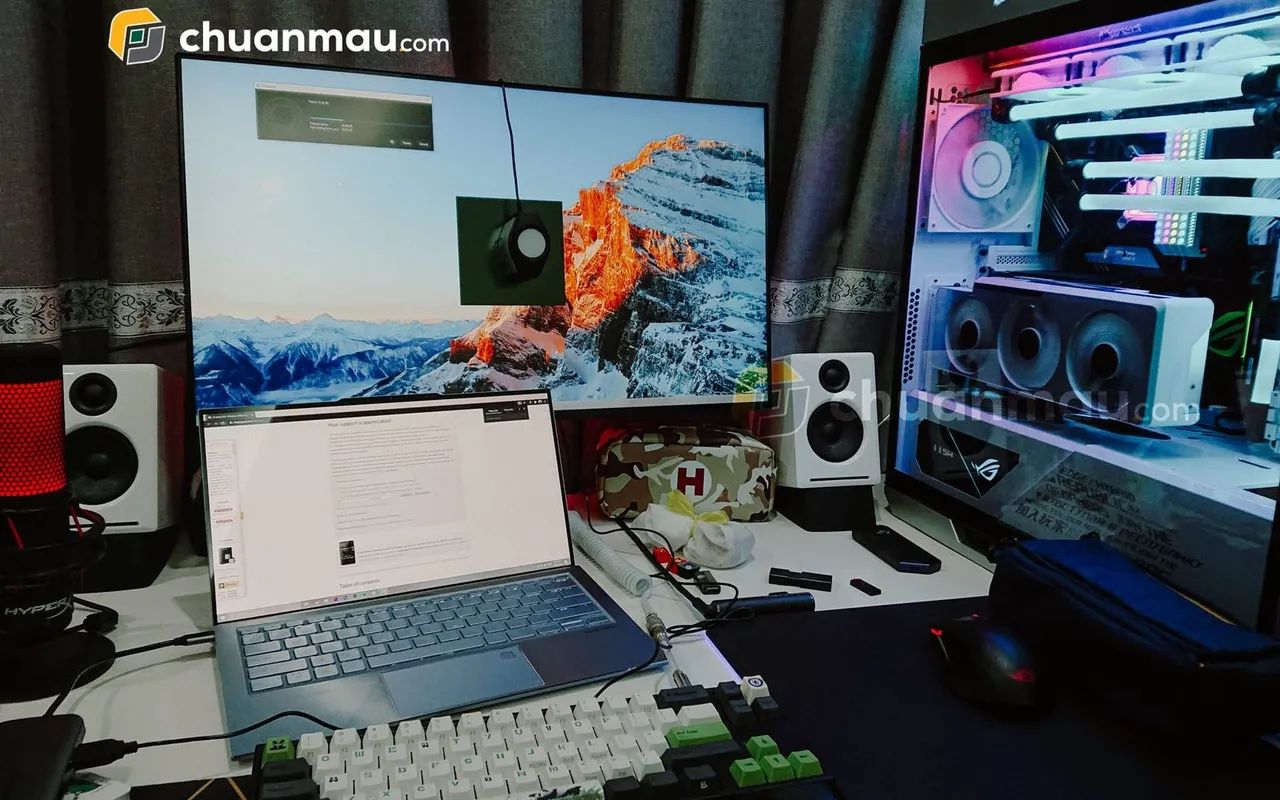 Thiết bị đo màu trên màn hình hiển thị ảnh núi tuyết, laptop mỏng mở bên dưới